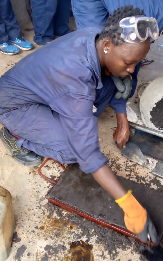 Woman filling brick mold with melted plastic and sand at Wan Pot Coal Enterprises