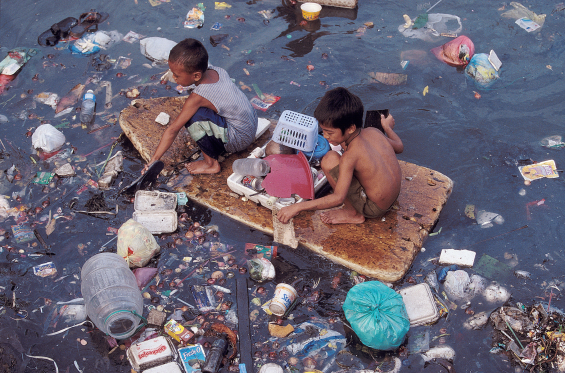 Boys on a home-made raft in a sea of plastic